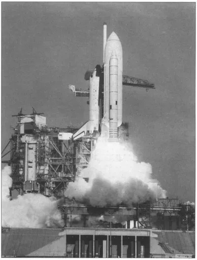 Black and white photo of NASA's Space Shuttle launching from Kennedy Space Center, with smoke and flames billowing from the boosters during liftoff.