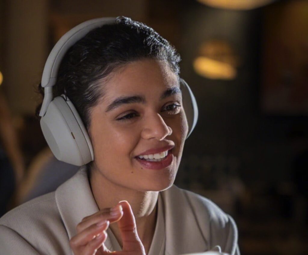 User wearing Sony WH-1000XM5 wireless noise-canceling headphones in a cozy indoor setting.